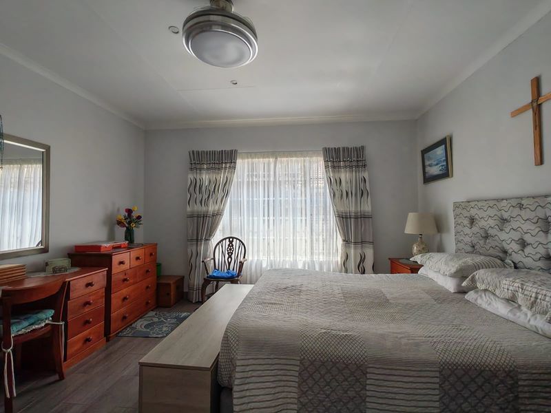 A well-lit bedroom featuring laminate flooring, a ceiling fan, and neutral wall finishes, providing a comfortable and functional sleeping space.