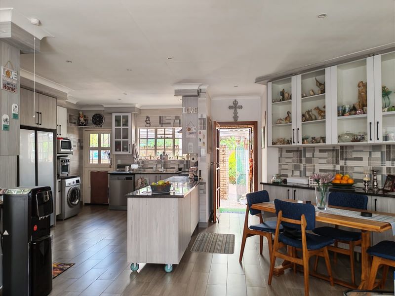 Spacious open-plan kitchen and dining area featuring modern cabinetry, a central island, tiled flooring, and direct access to the rear garden.