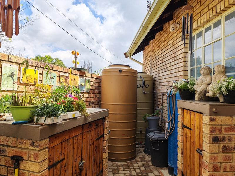A functional rear exterior area featuring brick walling, paved flooring, built-in storage cabinets, and installed water storage tanks.