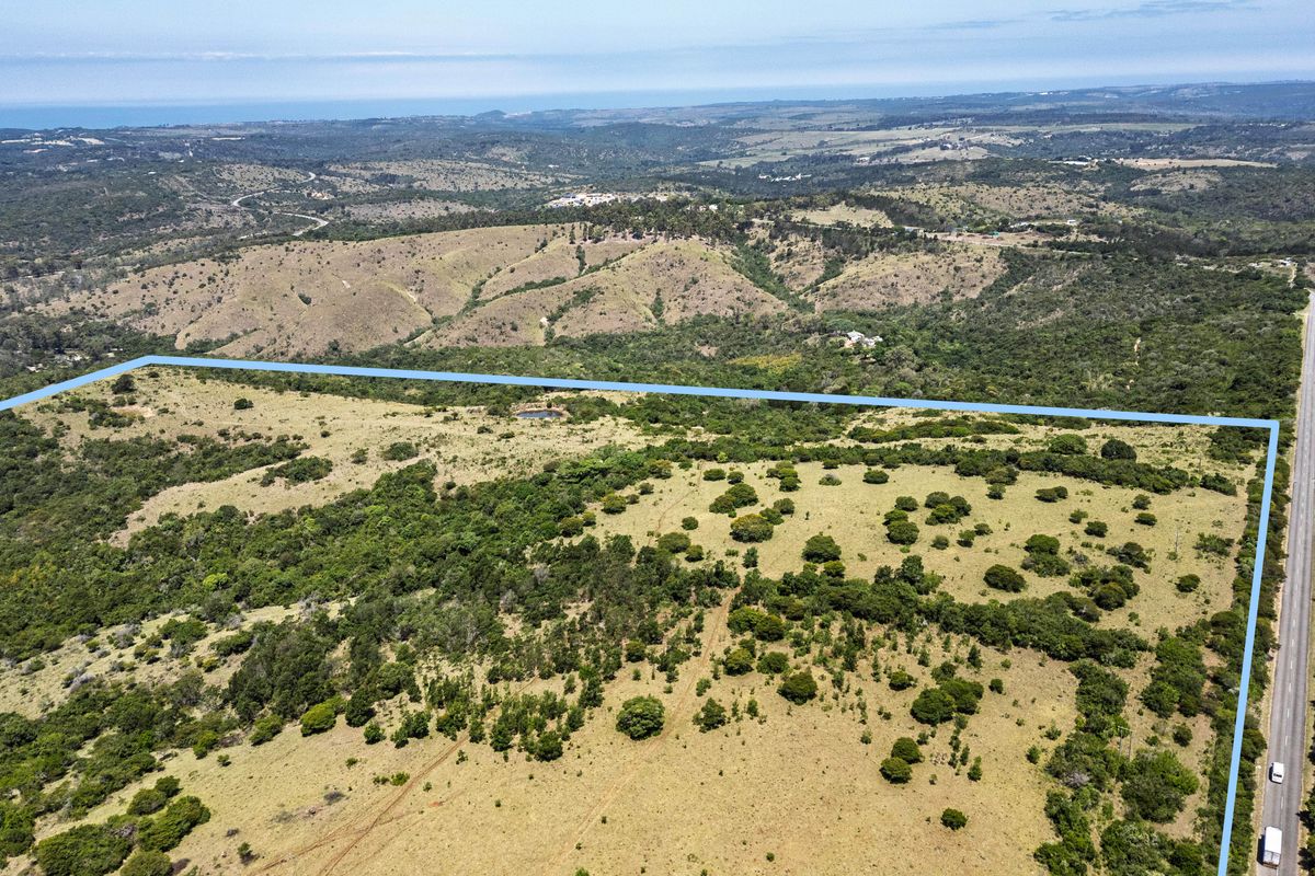An aerial view of a large, expansive farm property featuring natural vegetation and clear boundary lines adjacent to a main road.