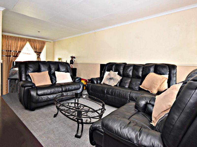 A living room featuring carpeted flooring, coved ceilings, and a dado rail, offering a functional space ready for cosmetic updates.