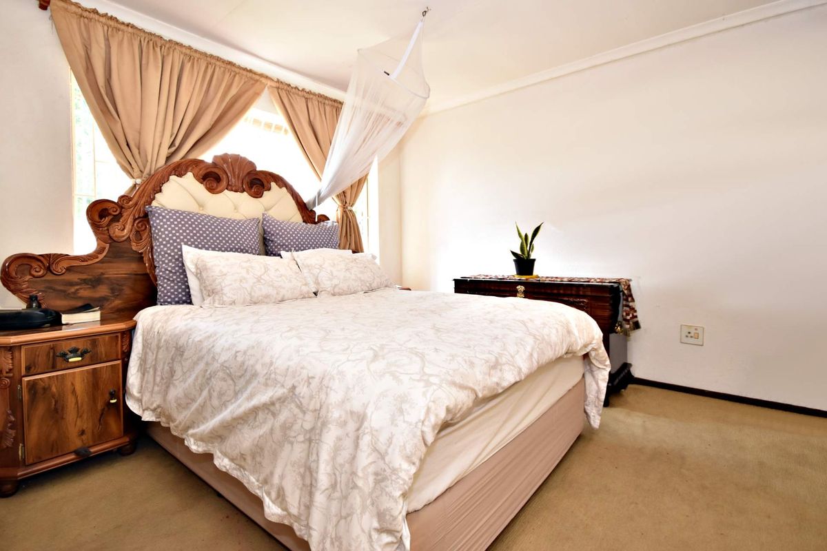 A well-lit bedroom featuring carpeted flooring and neutral wall finishes, providing a comfortable and functional sleeping space.
