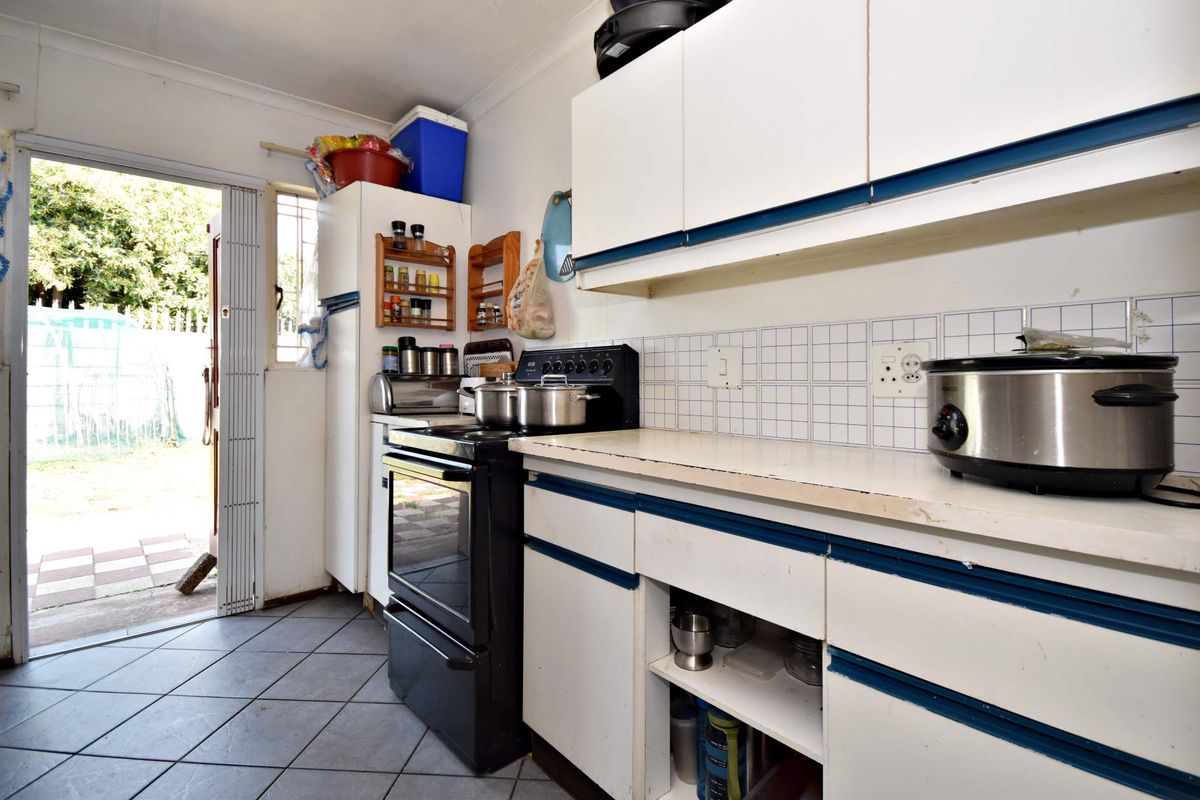 A functional kitchen featuring built-in cabinetry, a tiled backsplash, and a freestanding stove, with direct access to the rear exterior.