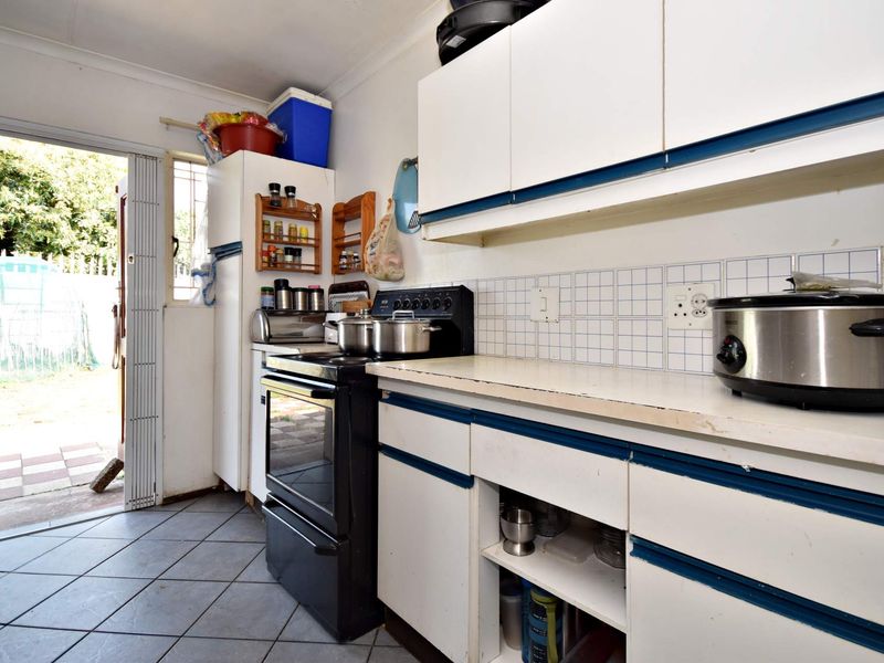 A functional kitchen featuring built-in cabinetry, a tiled backsplash, and a freestanding stove, with direct access to the rear exterior.