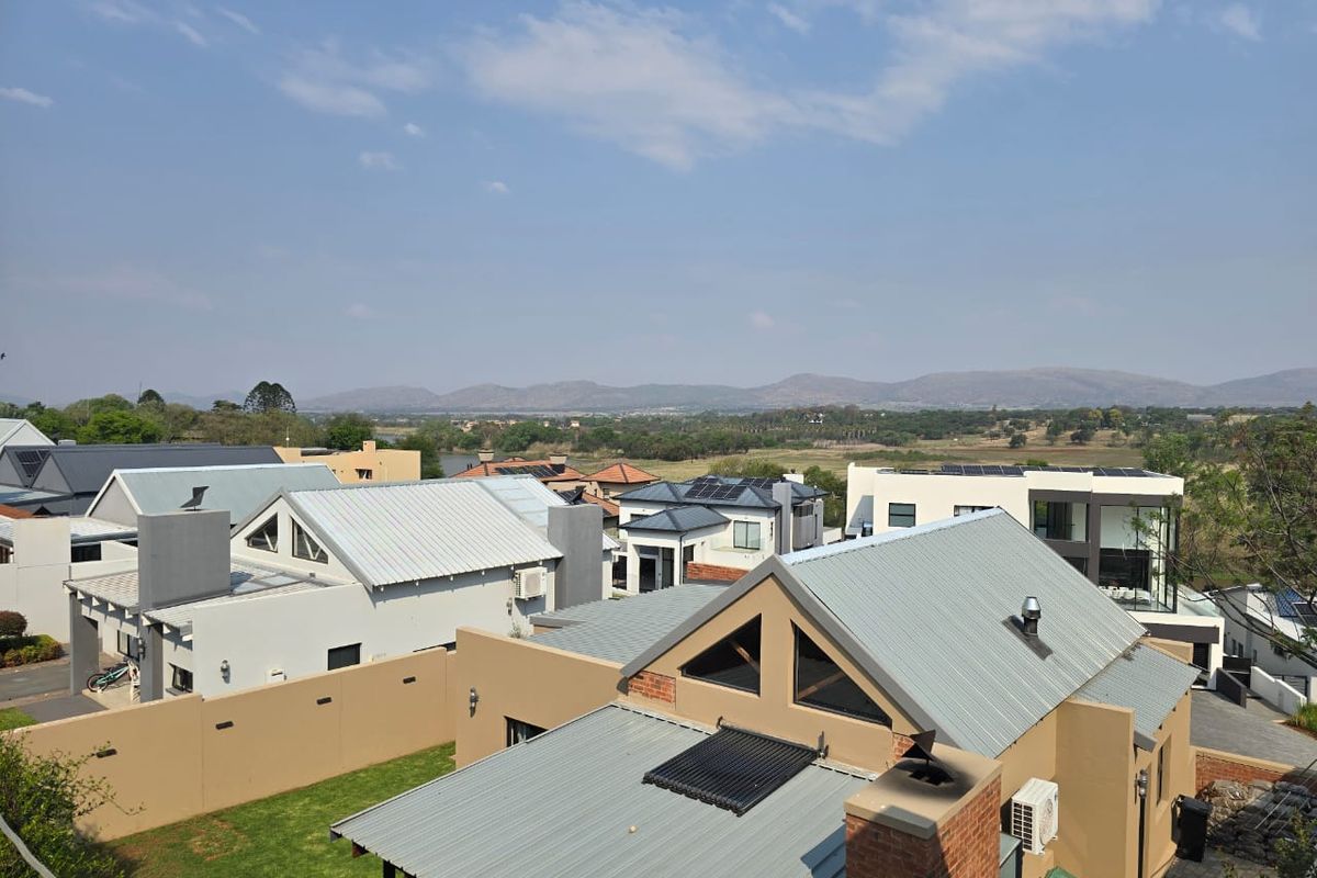 An elevated aerial view of the residential estate, showcasing modern homes with metal roofing, solar installations, and surrounding landscape views.