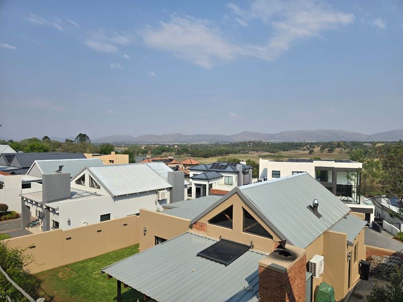 An elevated aerial view of the residential estate, showcasing modern homes with metal roofing, solar installations, and surrounding landscape views.