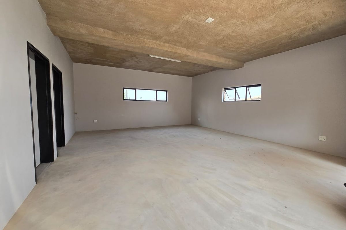 An expansive, unfinished interior space featuring raw concrete ceilings, cement flooring, and aluminium-framed windows, offering a blank canvas for custom interior design.