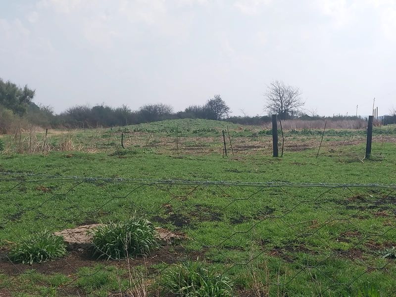 An expansive open plot of land featuring wire mesh and barbed wire perimeter fencing, suitable for agricultural or small holding development.