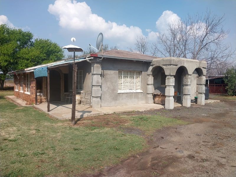 Front elevation of a small holding dwelling featuring a concrete porch with arched masonry columns and a metal roof structure.