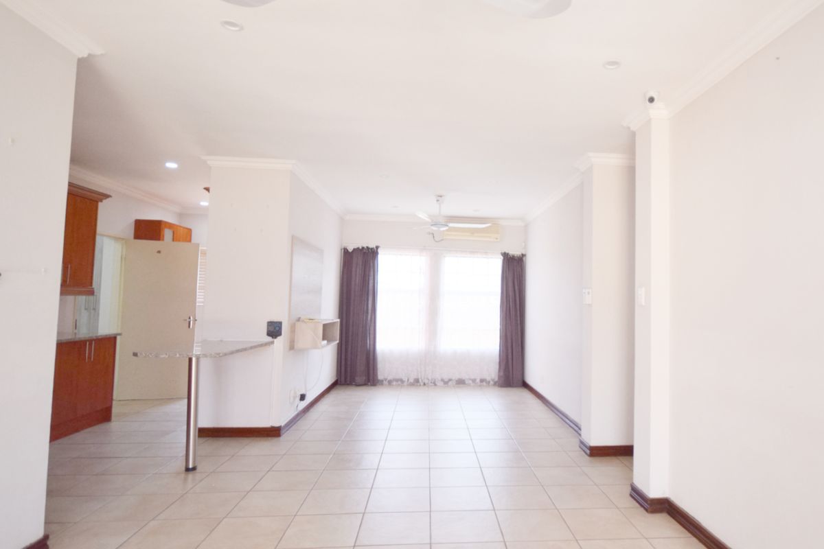 Spacious open-plan living area featuring tiled floors, a breakfast counter, and integrated kitchen cabinetry, offering a bright and versatile layout.