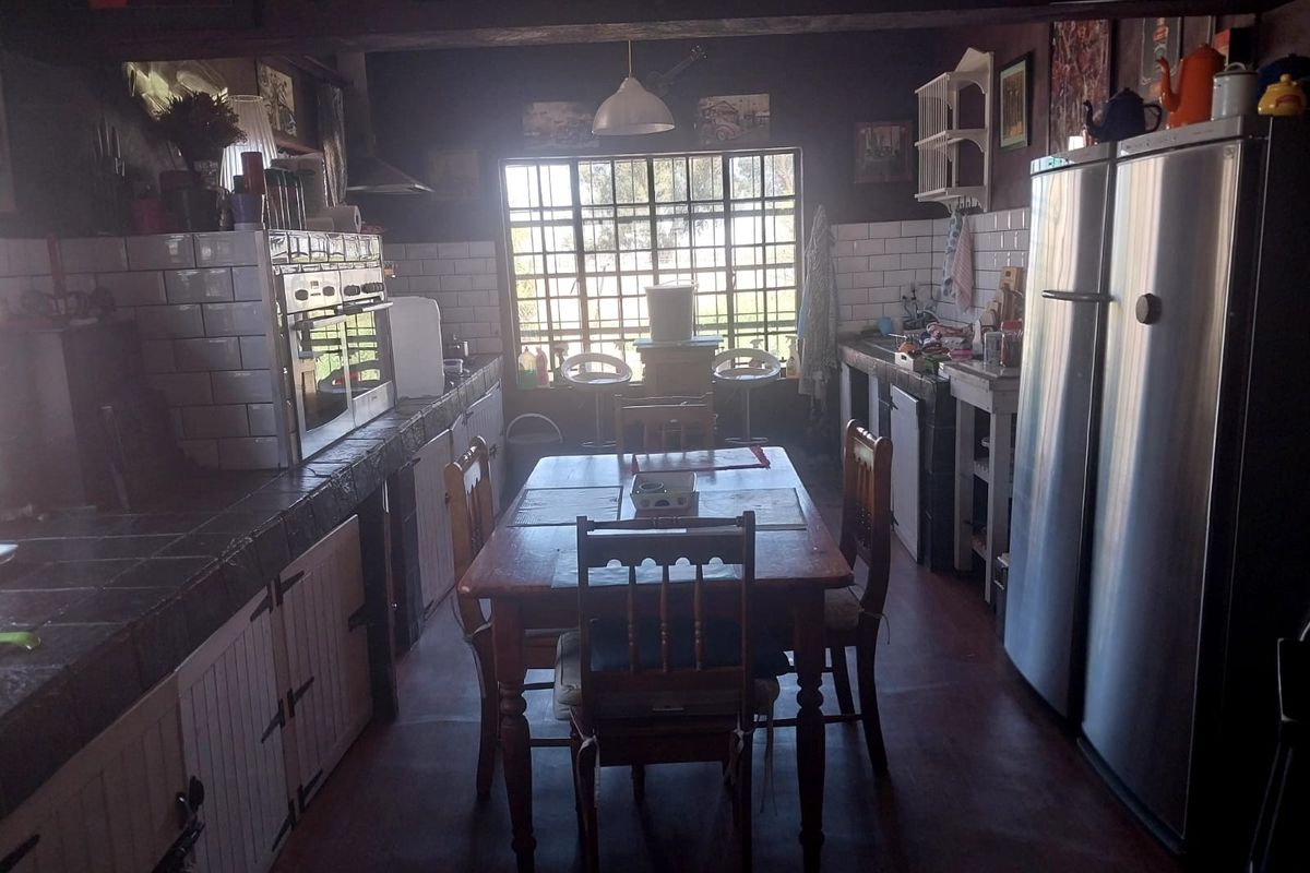 A rustic-style kitchen featuring tiled countertops, subway tile backsplash, and a large grid-pattern window, providing a functional workspace with a central dining area.