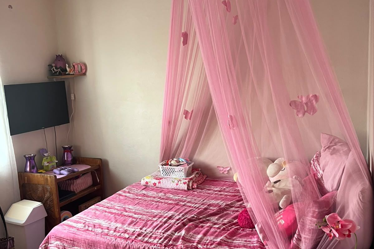 A bedroom featuring a standard layout with a built-in wall ventilation vent.
