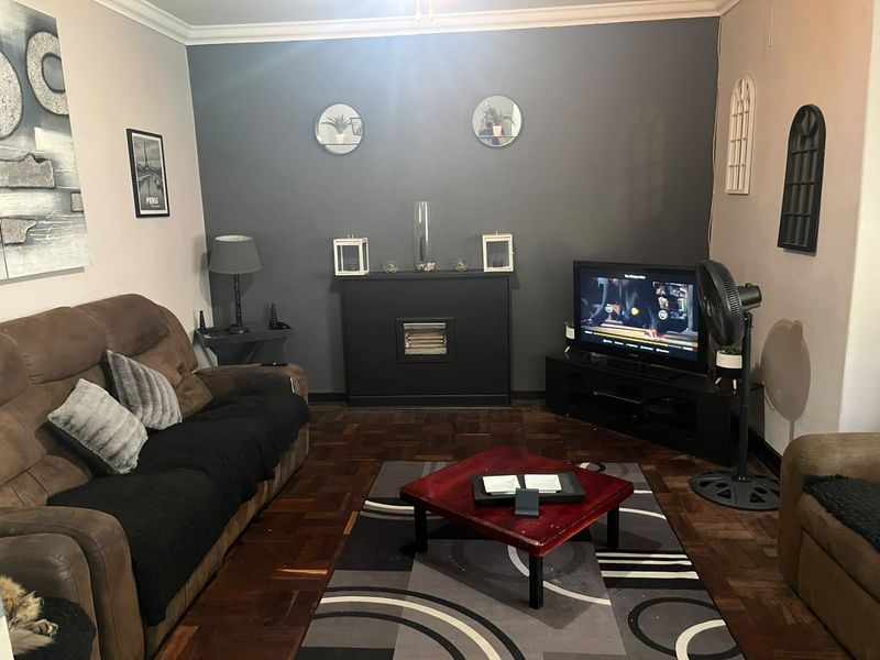 A cozy living room featuring classic parquet flooring, a central built-in fireplace, and decorative coving along the ceiling.