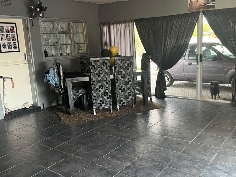 Spacious living area featuring dark tiled flooring, large sliding glass doors providing outdoor access, and neutral grey wall finishes.