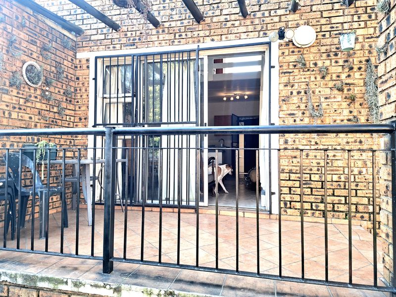 Covered patio area featuring exposed brick walls, tiled flooring, and a timber pergola, providing a seamless transition to the interior living space.