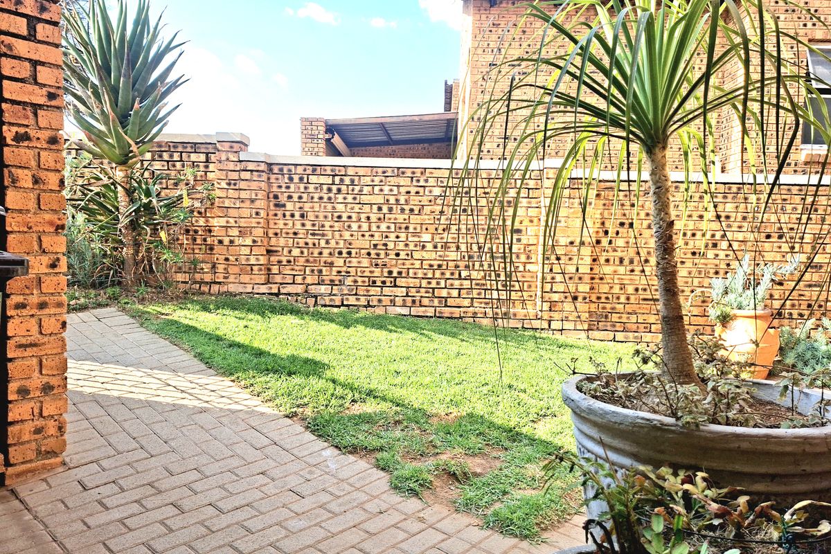 A private rear garden featuring a paved patio area, a small lawn, and face brick boundary walls.