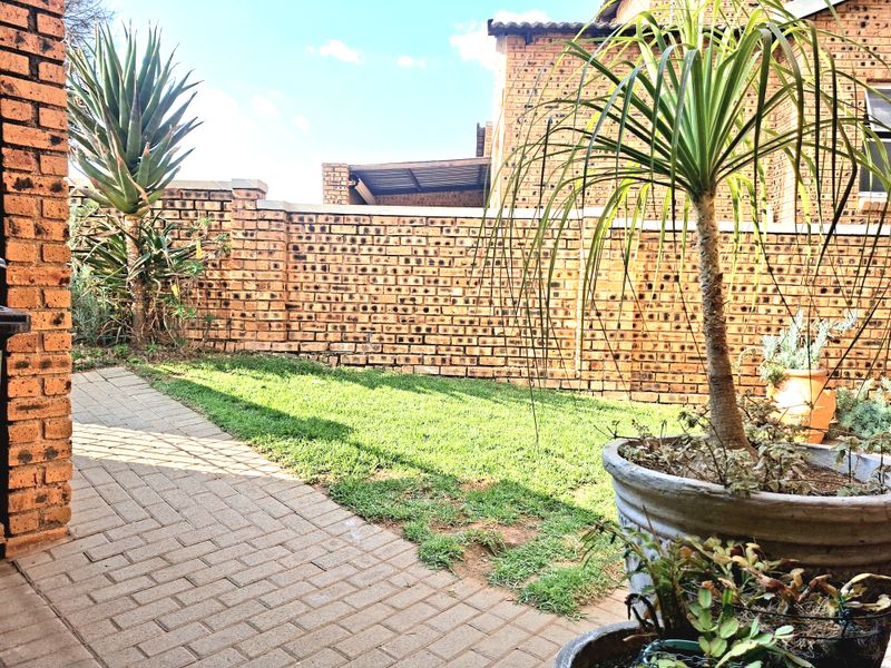 A private rear garden featuring a paved patio area, a small lawn, and face brick boundary walls.