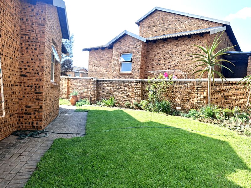 A private rear garden featuring a well-maintained lawn, paved walkway, and face brick boundary walls, providing a secure and low-maintenance outdoor space.