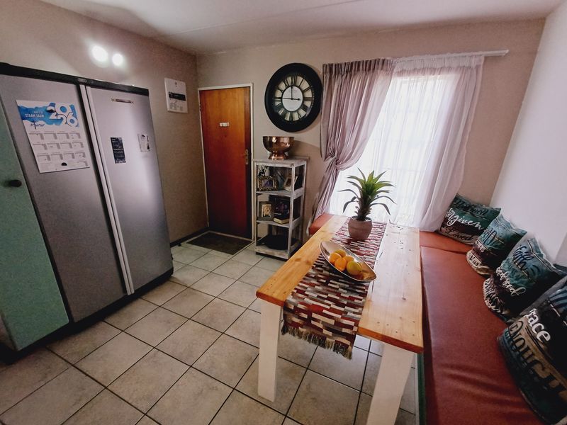 A dining area featuring tiled flooring, a window with curtain treatments, and access to an adjacent room.