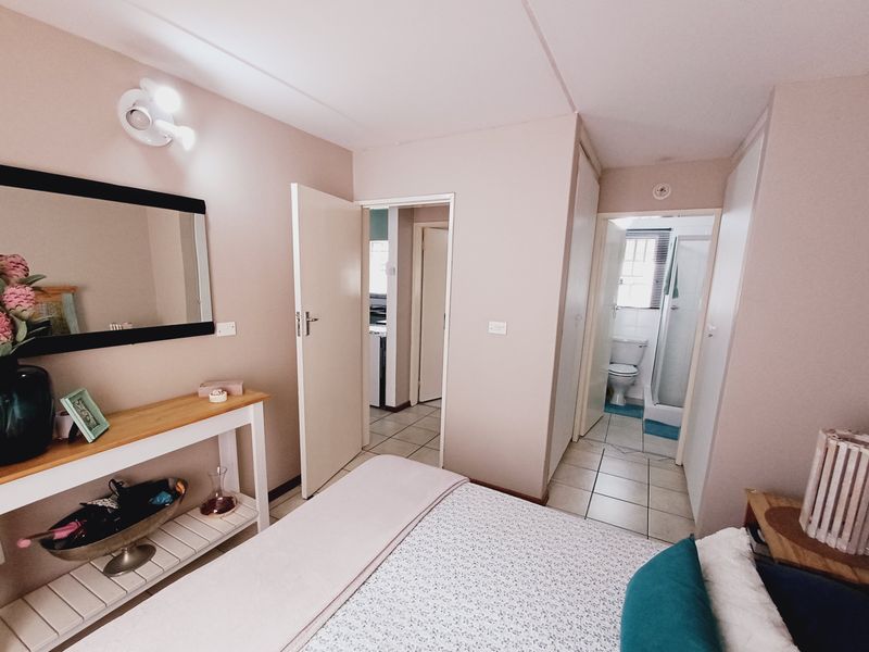 A well-maintained bedroom featuring tiled flooring, built-in storage, and direct access to an en-suite bathroom.
