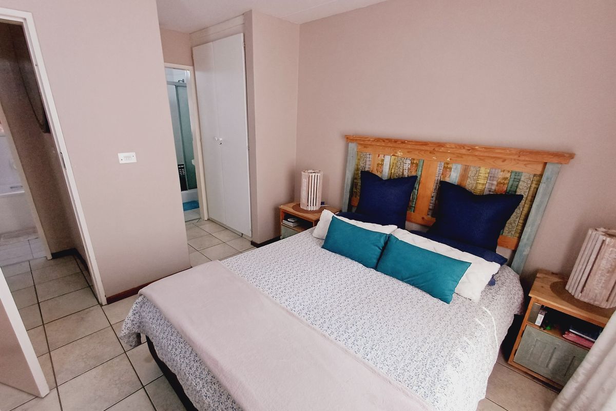 A bedroom featuring tiled flooring and a built-in cupboard, with an adjoining bathroom visible through the doorway.