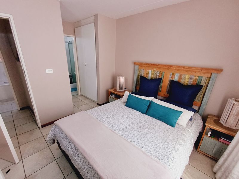 A bedroom featuring tiled flooring and a built-in cupboard, with an adjoining bathroom visible through the doorway.
