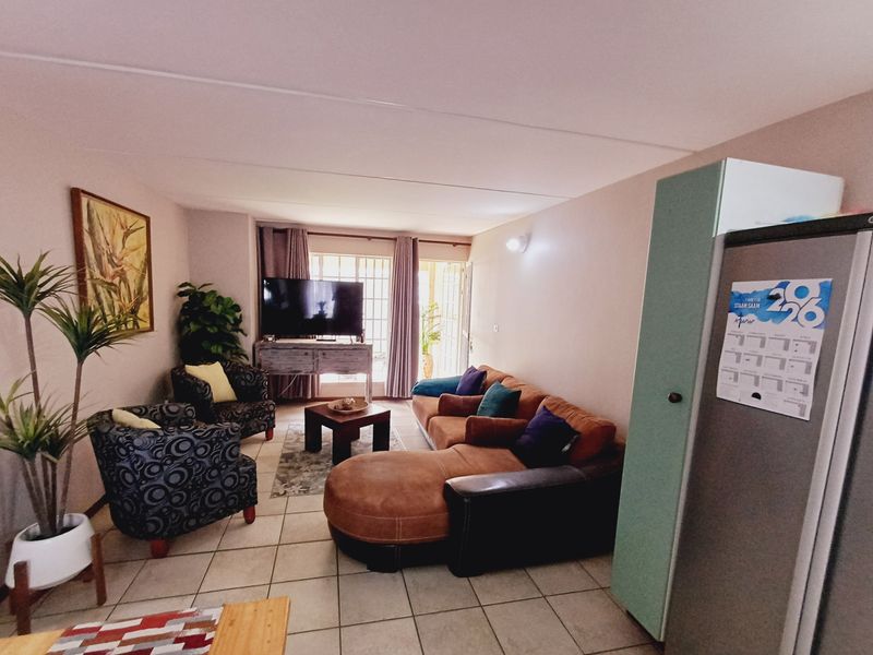 A living room area featuring tiled flooring and a sliding glass door leading to an outdoor space.