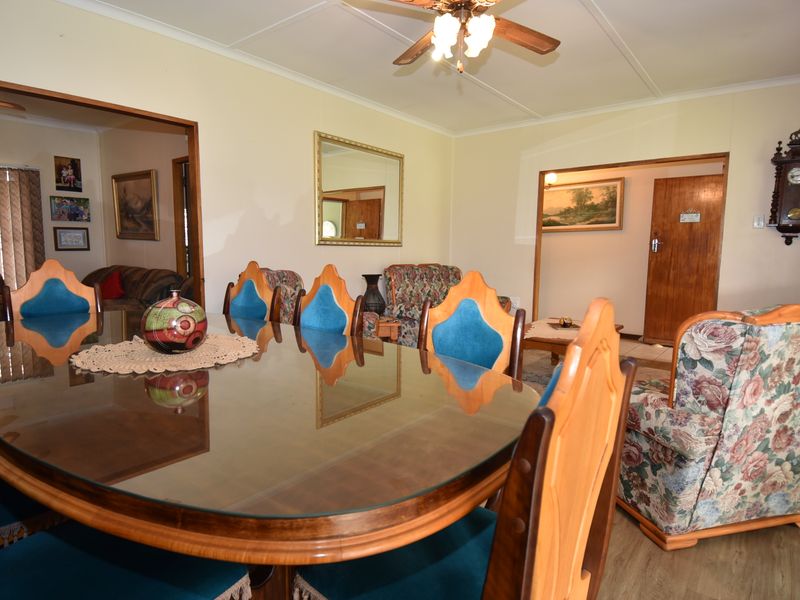 A spacious dining area featuring laminate flooring, a ceiling fan, and direct access to adjacent living spaces.