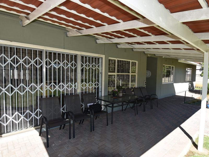 A covered patio area featuring paved flooring, security gates, and sliding doors, providing a functional outdoor space for relaxation.