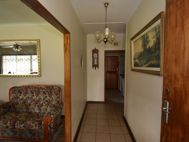 A functional hallway featuring tiled flooring and timber door frames, providing access to adjacent living and utility areas.