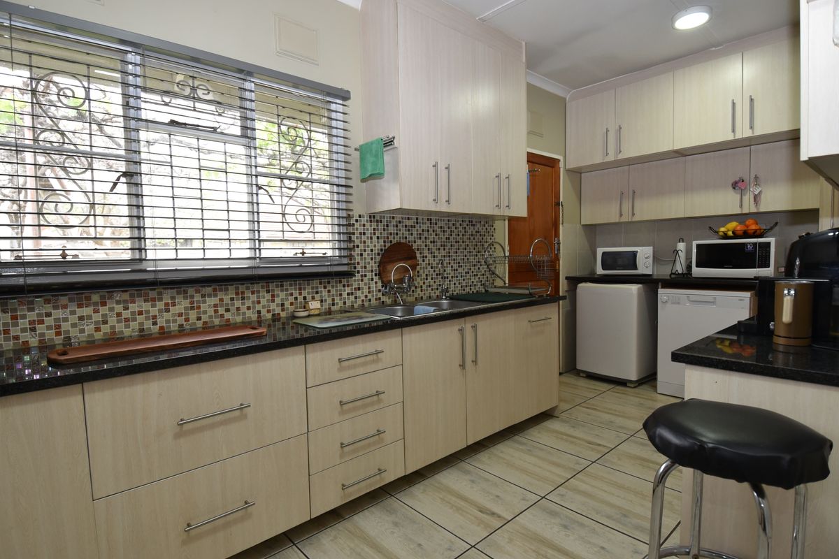 A functional kitchen featuring light wood-finish cabinetry, granite countertops, mosaic tile backsplash, and tiled flooring with ample storage space.