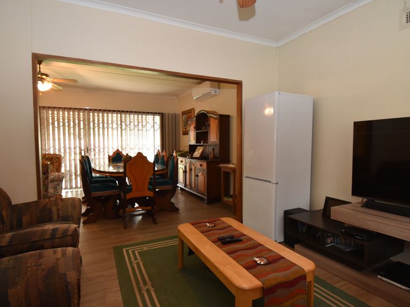 Open plan living and dining area featuring laminate flooring, ceiling fan, and split system air conditioning, connecting to a rear patio space.