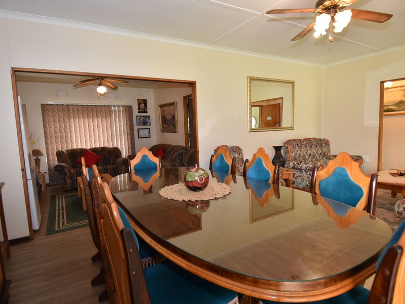 Open plan dining and living area featuring laminate flooring and ceiling fans, providing a functional and connected living space.