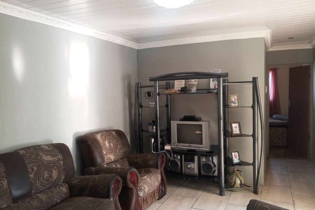A living room featuring tiled flooring and a tongue and groove ceiling with decorative cornice detailing.