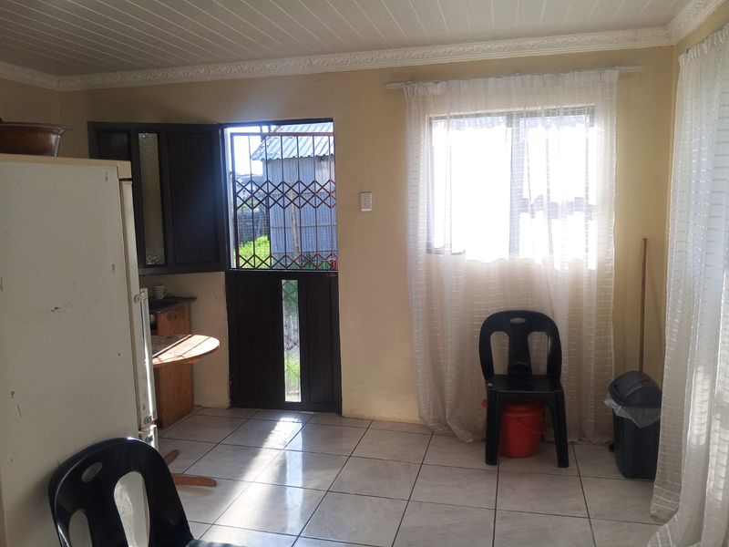A functional kitchen area featuring tiled flooring, a timber ceiling, and a security gate leading to the exterior.