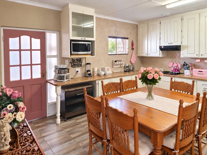 Open-plan kitchen and dining area featuring traditional cabinetry, tiled backsplash, and integrated appliances, providing a functional and connected living space.