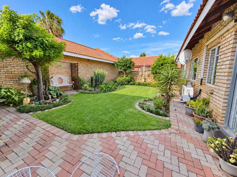 A well-maintained rear garden featuring brick paving, a manicured lawn, and established perimeter brick walls, providing a private outdoor space.
