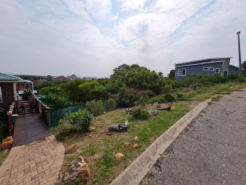 A view of the residential property frontage featuring a paved walkway, timber decking, and established garden landscaping.