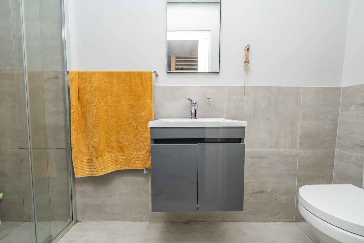 Modern bathroom featuring a wall-mounted vanity, glass shower enclosure, neutral wall tiling, and contemporary fixtures.