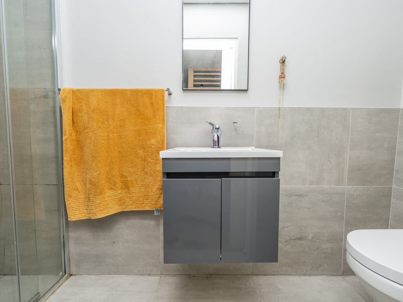 Modern bathroom featuring a wall-mounted vanity, glass shower enclosure, neutral wall tiling, and contemporary fixtures.