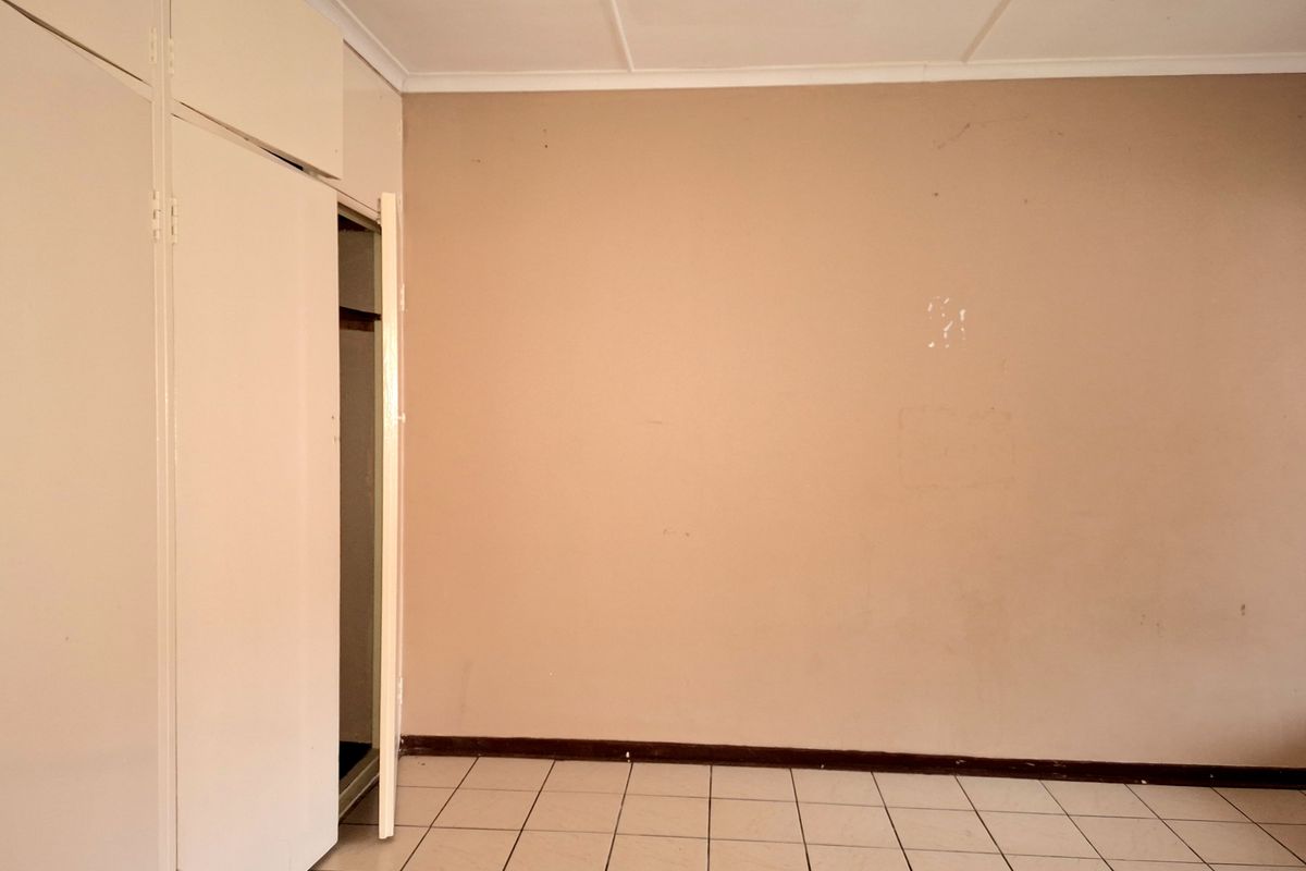 An empty bedroom featuring tiled flooring and built-in cupboards, presenting a blank canvas ready for personalization and cosmetic updates.