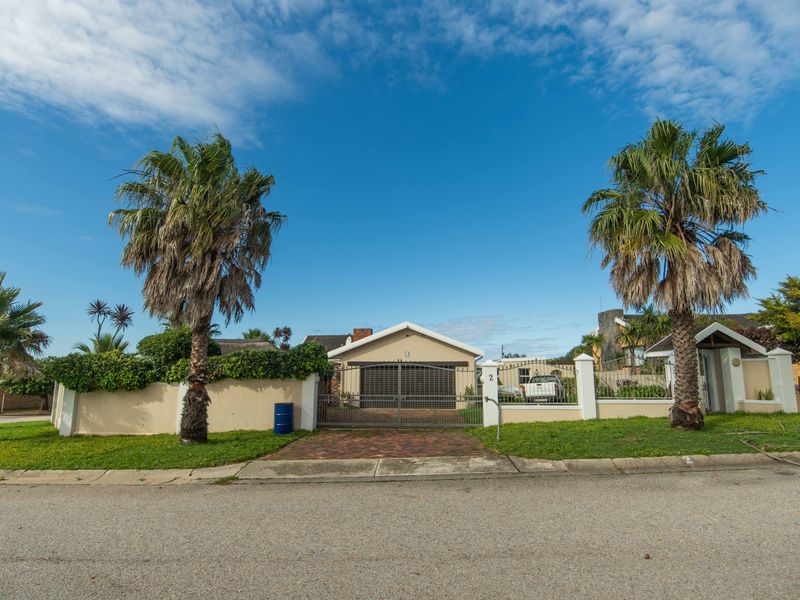 Front elevation of a residential property featuring a paved driveway, secure metal gate, perimeter wall, and a single garage.