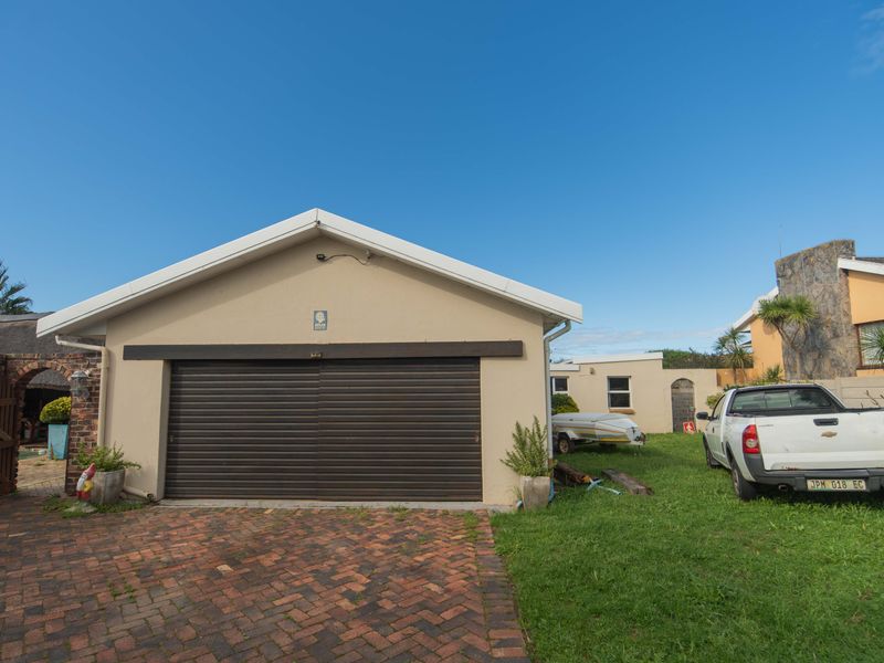 Exterior view of a detached garage with a roll-up door and brick paved driveway, situated on a residential property.