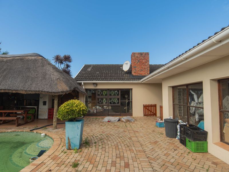Outdoor entertainment area featuring a swimming pool, a traditional thatched lapa, and brick-paved patio space with direct access to the main house.
