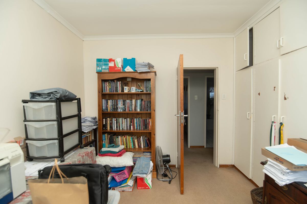 A bedroom featuring built-in cupboards, carpeted flooring, and coved ceilings, offering a functional space ready for modernization and updated finishes.