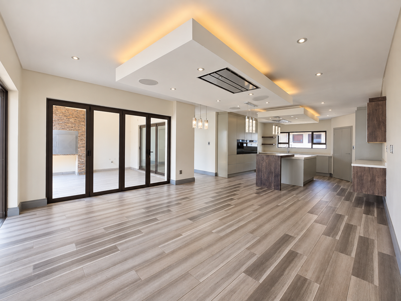 Spacious open-plan living and kitchen area featuring modern cabinetry, a central island, recessed ceiling lighting, and large sliding doors leading to an outdoor patio.