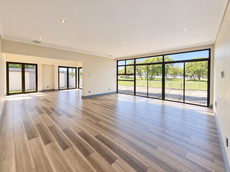 Spacious open-plan living area featuring modern wood-look tile flooring, recessed lighting, and expansive sliding glass doors providing abundant natural light and garden access.