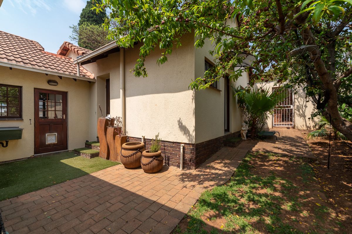 A well-maintained rear exterior area featuring brick paving, a tiled roof, and a secure entrance with a pet door.