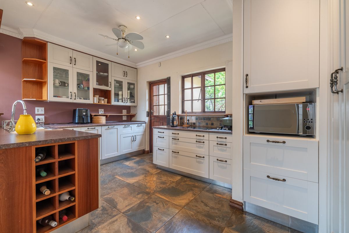 A functional kitchen featuring white cabinetry, laminate countertops, built-in wine storage, a built-in microwave, and tiled flooring with direct outdoor access.