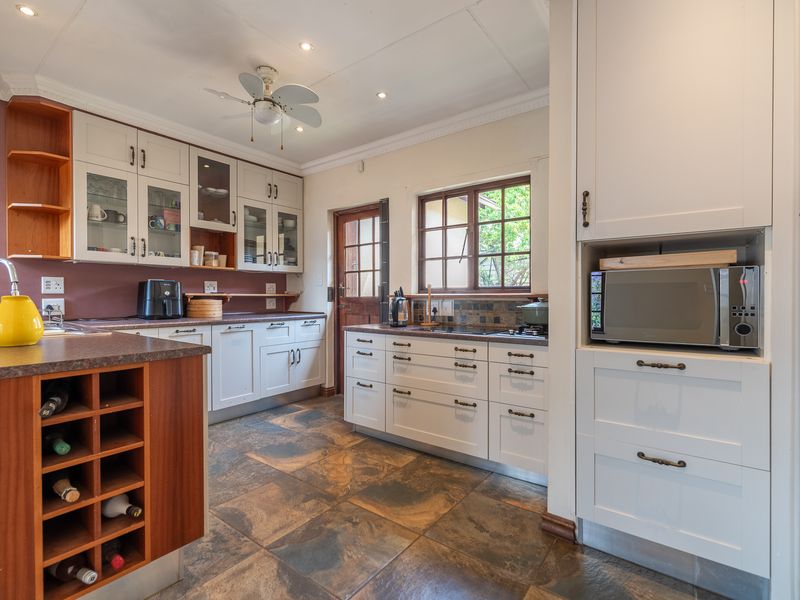 A functional kitchen featuring white cabinetry, laminate countertops, built-in wine storage, a built-in microwave, and tiled flooring with direct outdoor access.